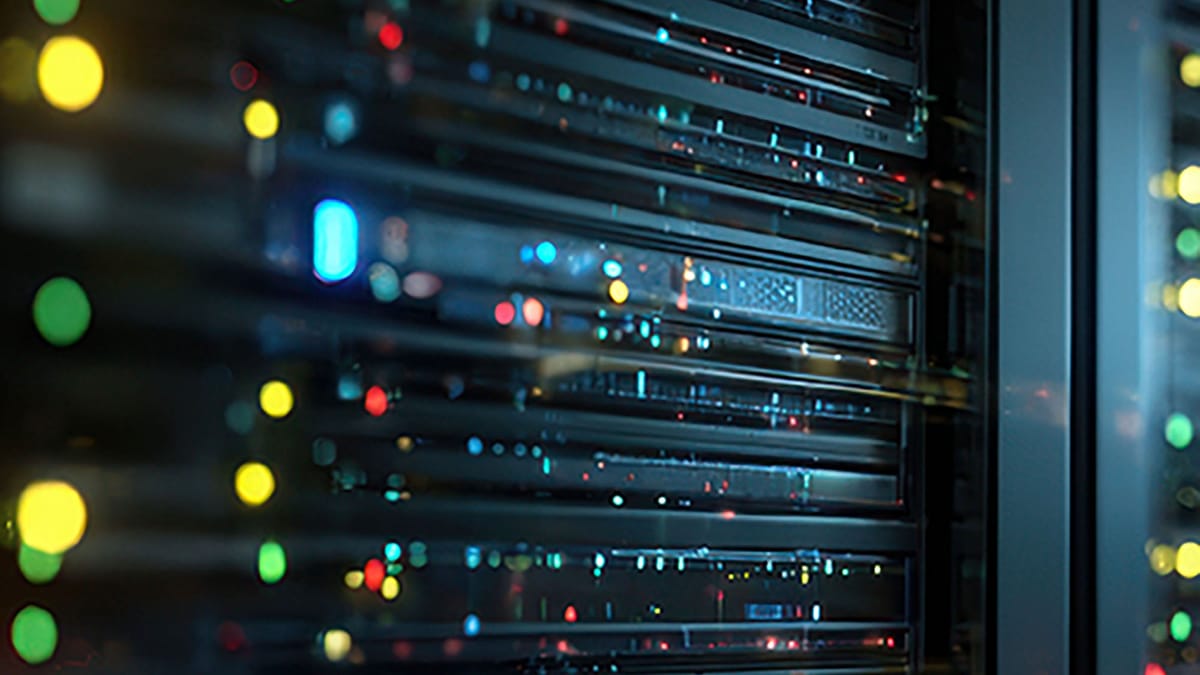 Rows of server racks in a data centre, lit by blinking indicator lights.